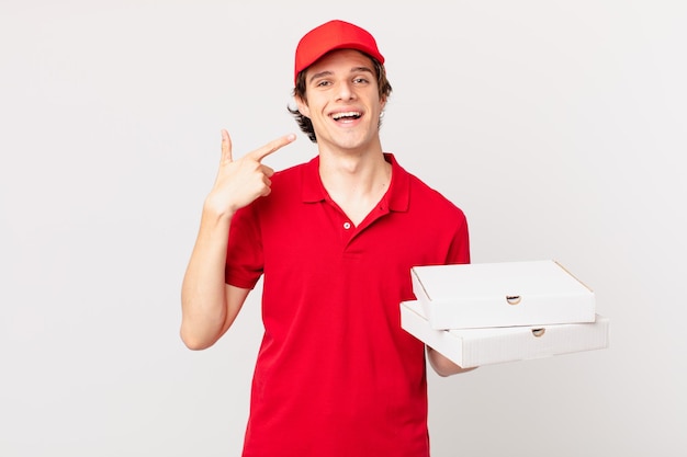 Repartidor de pizzas sonriendo confiadamente apuntando a su propia sonrisa amplia