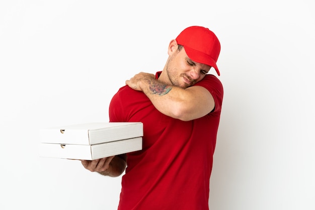 Foto repartidor de pizzas con uniforme de trabajo recogiendo cajas de pizza sobre una pared blanca aislada que sufre de dolor en el hombro por haber hecho un esfuerzo