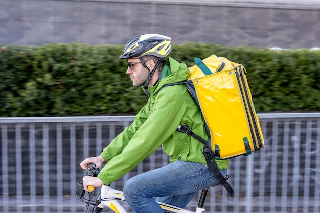 Repartidor rápido montando en la ciudad joven mensajero vestido con ropa técnica y deportiva con casco y mochila para el efecto paneo de alimentos entregas a domicilio rápidas y urgentes nuevos negocios