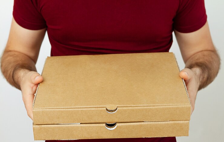 Repartidor en rojo t-short con cajas de cartón de pizza sobre fondo blanco. Delivery de pizza. Mensajero a casa.