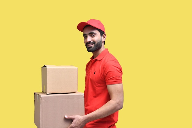 Repartidor sonriendo en camiseta roja y gorra con caja de embalaje modelo paquistaní indio