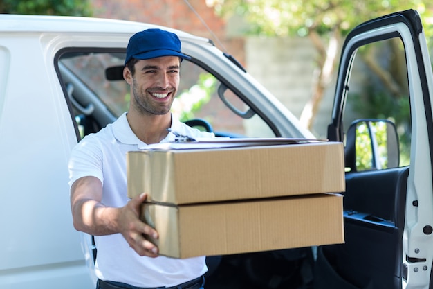 Repartidor sonriente dando cajas de cartón