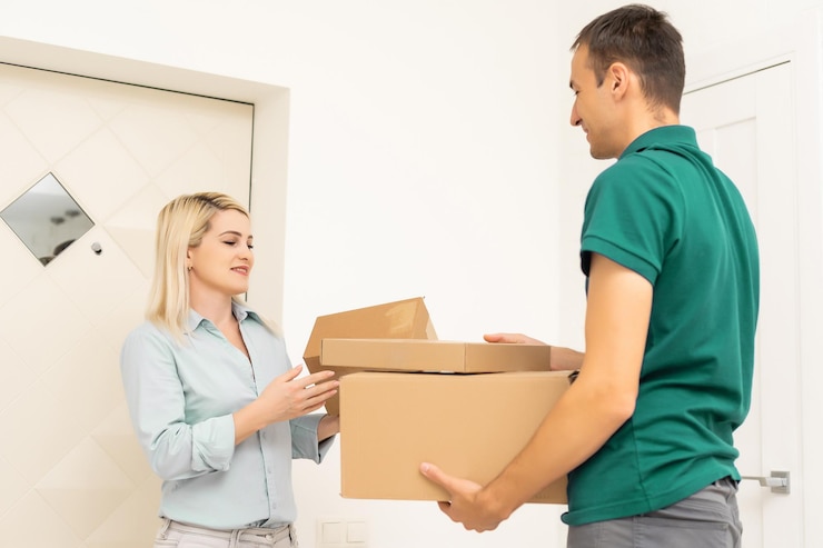 Foto repartidor sonriente dando cajas a la clienta en casa para el concepto de servicio de compras en línea