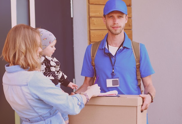Repartidor sonriente con uniforme azul entregando cajas de paquetes al concepto de servicio de mensajería del destinatario Repartidor sonriente con uniforme azul