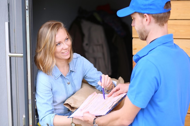Repartidor sonriente en uniforme azul que entrega la caja del paquete al concepto de servicio de mensajería del destinatario