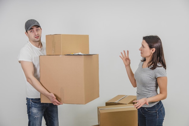 El repartidor transportó todas las cajas de cartón al nuevo apartamento de la mujer pero demasiado tarde y la mujer está irritada debido a esto el mensajero está mirando con una expresión facial inocente
