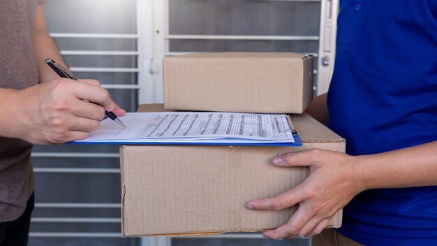 Repartidor en uniforme azul entrega caja de paquetería para el cliente