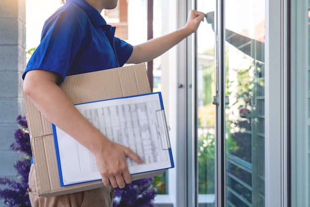 Foto repartidor en uniforme azul que entrega la caja del paquete para la lista de verificación de firma del cliente