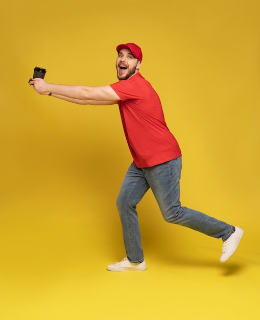 Repartidor en uniforme de camiseta en blanco de gorra roja aislado en la pared amarilla