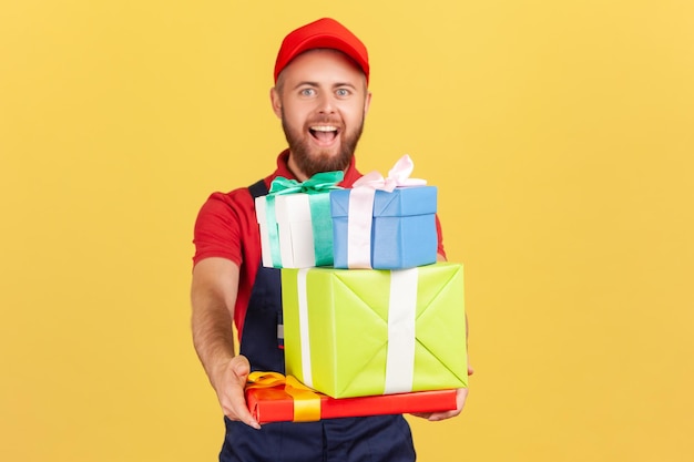 Repartidor con uniforme y gorra roja dando muchas cajas de regalo al cliente entrega puerta a puerta