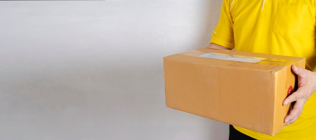 Repartidor en uniforme naranja entregando una caja de paquetes a un concepto de servicio de mensajería al cliente