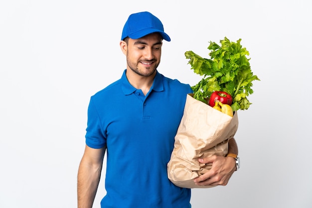 Repartidor con verduras aislado en la pared blanca con expresión feliz