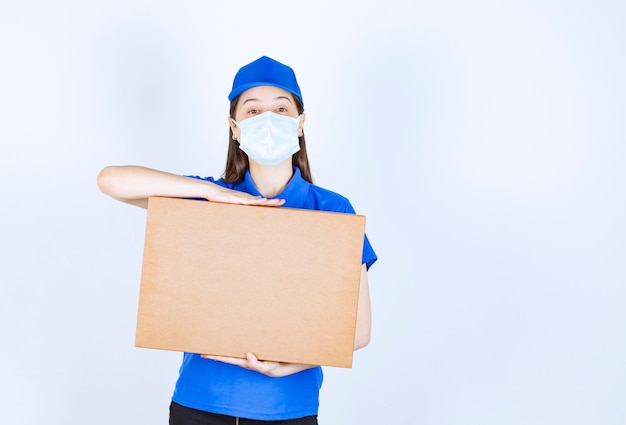 Repartidora joven en máscara médica con paquete de cartón.