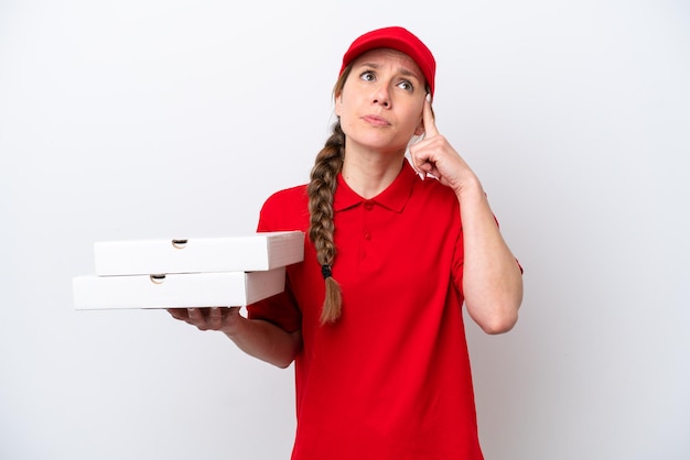 Repartidora de pizza con uniforme de trabajo recogiendo cajas de pizza aisladas de fondo blanco con dudas y pensando
