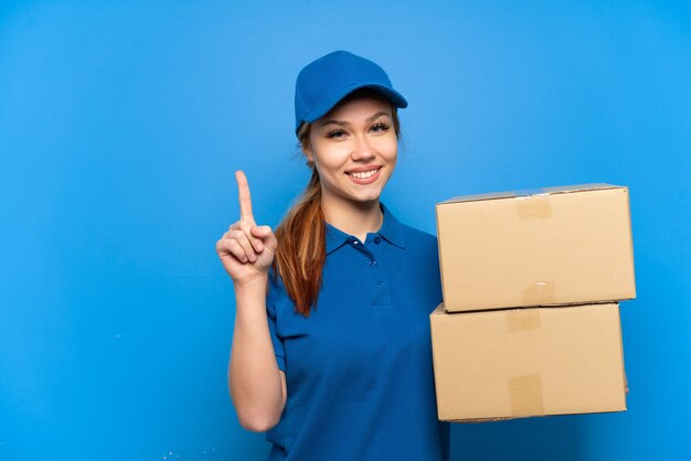 Repartidora sobre pared azul aislada mostrando y levantando un dedo en señal de lo mejor