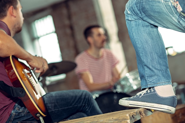 Foto repetição de banda de rock. baixista, guitarrista e baterista no loft. música rock e conceito de jam session. paixão pela música e conceitos de cultura jovem