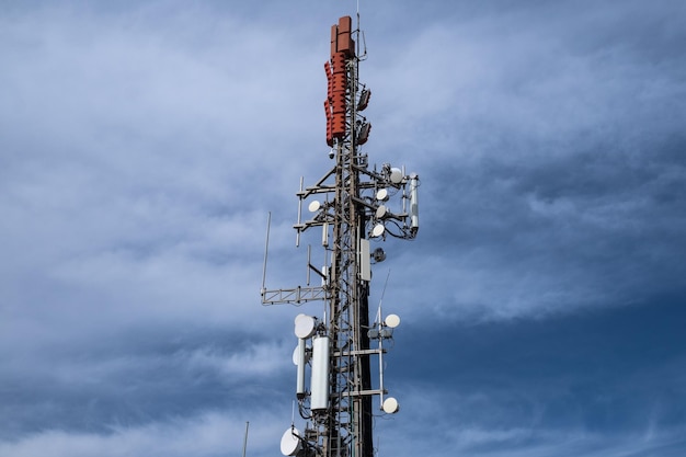 Repetidor de torre de comunicação com céu azul e nuvens brancas ao fundo