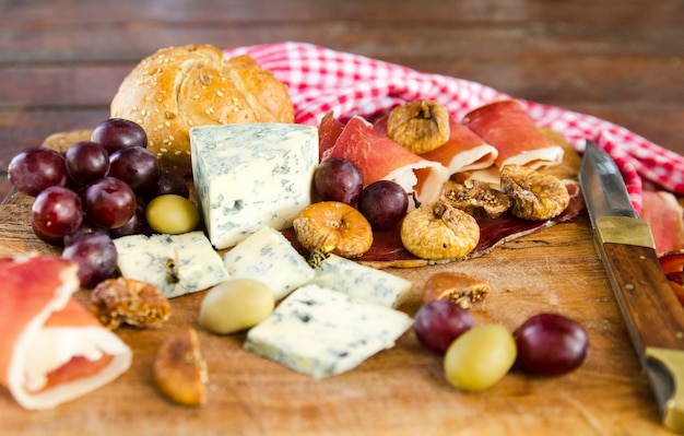 Repolho gourmet tradicional ou refeição de aperitivo em placa de madeira. Queijo azul, uva, presunto e frutas doces.