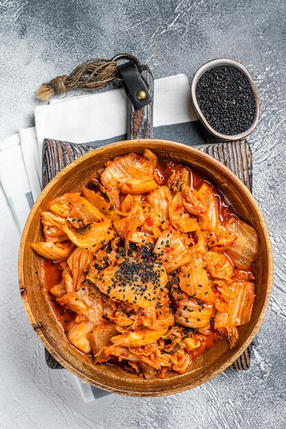 Repolho Kimchi em uma placa de madeira com pauzinhos para comer cozinha coreana Fundo branco Vista superior