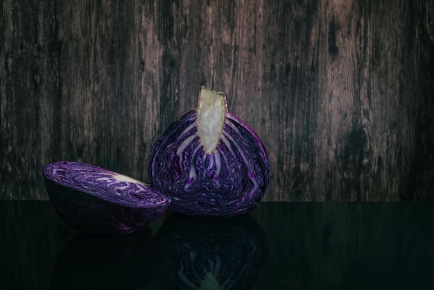 Repolho roxo cortado na mesa preta e fundo de madeira