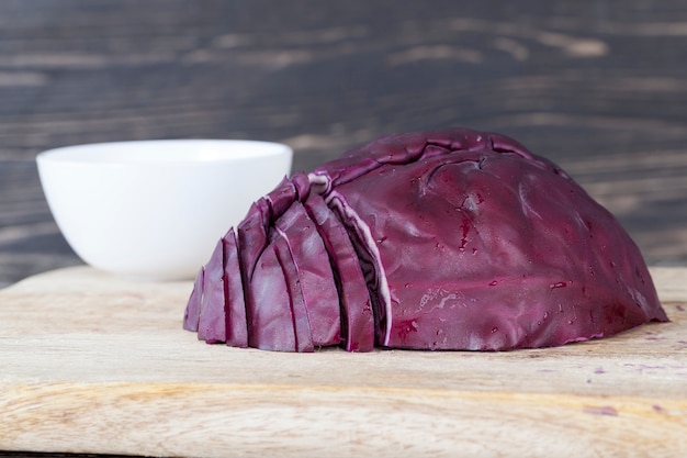 Repolho roxo picado em uma tábua de madeira durante o preparo da salada