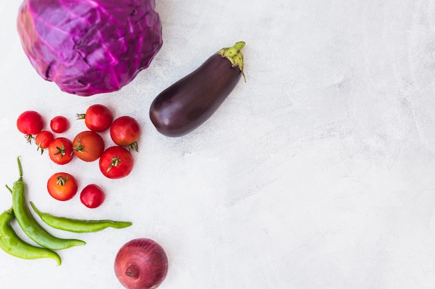 Repollo rojo; los tomates chiles verdes; Cebolla y berenjena sobre fondo blanco con textura