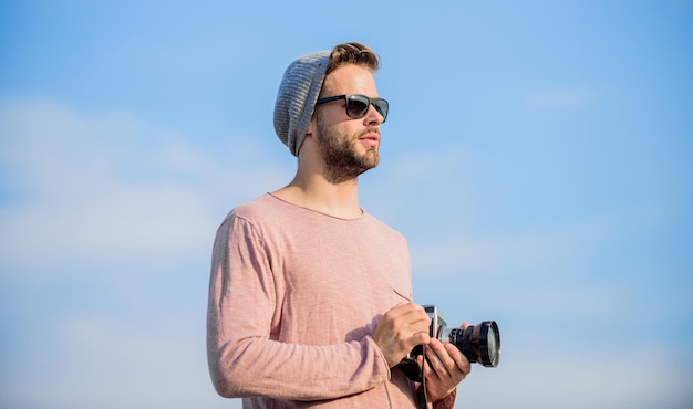 Reportaje fotográfico captura periodista de aventuras hombre sexy reportero turístico fotógrafo con gafas hombre macho con cámara viaje con cámara estilo de moda masculino que se ve moderno