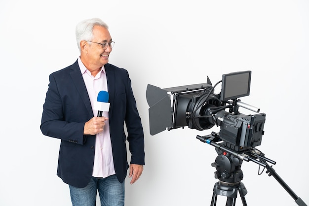 Reporter Brasilianischer Mann mittleren Alters, der ein Mikrofon hält und Nachrichten isoliert auf weißem Hintergrund mit Blick auf die Seite meldet