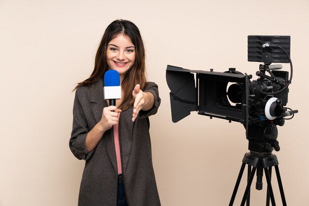 Repórter mulher segurando um microfone e relatando notícias sobre parede aperto de mão depois de bom negócio