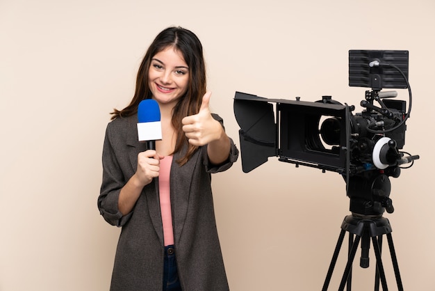 Repórter mulher segurando um microfone e reportar notícias sobre parede dando um polegar para cima gesto