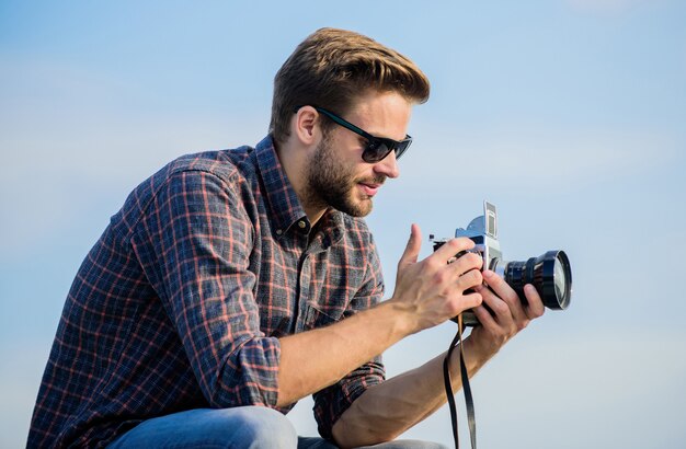 Repórter tirando foto Homem ao ar livre fundo de céu azul Equipamento vintage Blogger tiro vlog