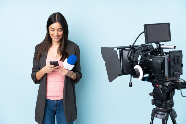 Reporterfrau, die ein Mikrofon hält und Nachrichten auf Blau isoliert berichtet