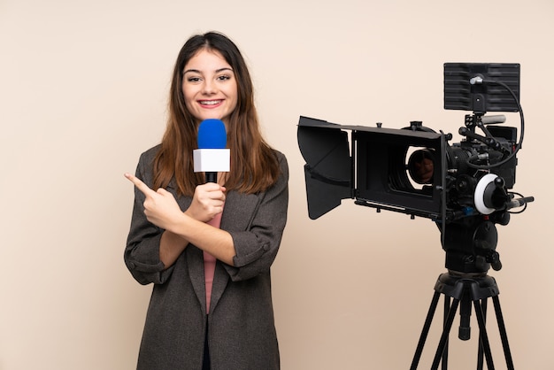 Reporterfrau, die ein Mikrofon hält und Nachrichten über Wand berichtet, die Finger zur Seite zeigt