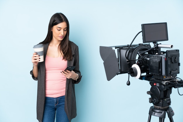 Reporterin, die ein Mikrofon hält und Nachrichten über Blau hält, das Kaffee zum Mitnehmen und ein Handy hält