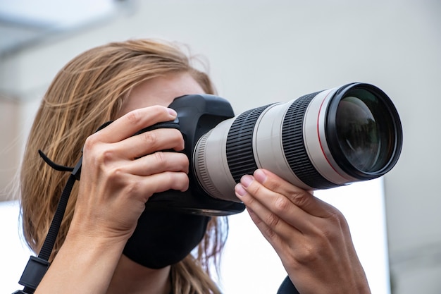 Reporterin mit einer Kamera. Arbeit eines Fotografen. Aufnahmematerial für Neuigkeiten.