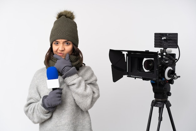 Reportero mujer sosteniendo un micrófono y reportando noticias sobre fondo blanco aislado pensando