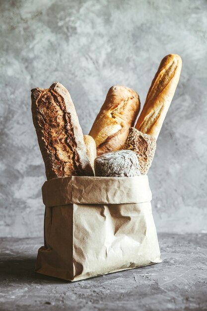 Repostería francesa, baguettes sobre un fondo gris en una bolsa de papel.