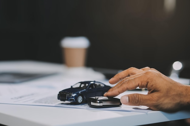 El representante de ventas de automóviles da las llaves al nuevo propietario del automóvil concepto para el alquiler de automóviles Centrarse en la llave Recoger la llave Primer plano de la transferencia de la llave de la máquina nueva al comprador