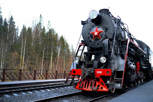 República da Carélia, Rússia - locomotiva a vapor soviética da série L com o trem turístico Ruskealsky Express na plataforma da estação ferroviária do cânion de mármore.