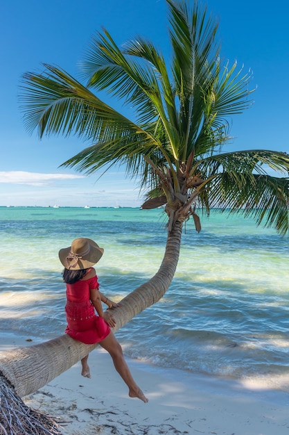 República Dominicana de Punta Cana, uma garota de chapéu no oceano com água turquesa e palmeiras