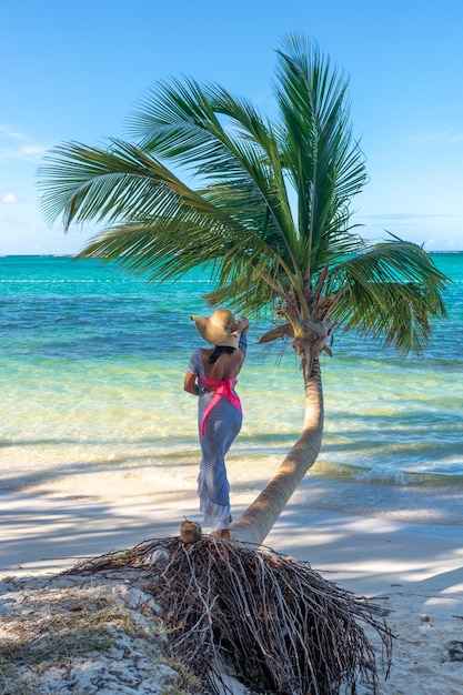 República Dominicana de Punta Cana, uma garota de chapéu no oceano com água turquesa e palmeiras