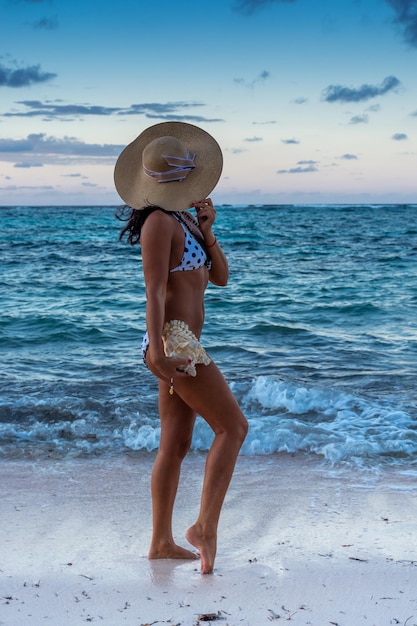 República Dominicana de Punta Cana, uma garota de chapéu no oceano com água turquesa e palmeiras
