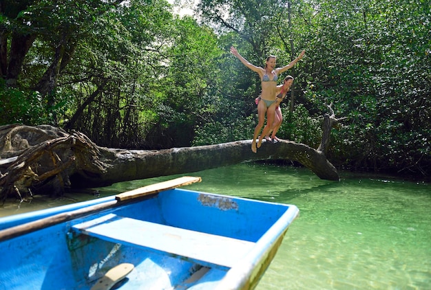 República Dominicana, Samaná, dos mujeres saltando al agua en una laguna de manglares