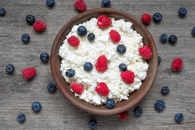 Requesón con frambuesas frescas y arándanos en un tazón para un desayuno saludable