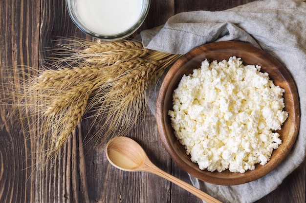 Requesón, leche y espigas de trigo en la mesa de madera rústica. Productos lácteos para la festividad judía de Shavuot. Vista superior.