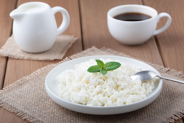 Requesón en un plato de café y leche en una mesa de madera