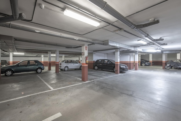 Rés-do-chão de um edifício dedicado a uma garagem com piso de cimento e espaços marcados a tinta branca