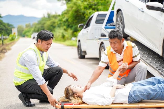 Rescate ayudando a una mujer conductora de un accidente automovilístico en la carretera con un accidente automotriz en el camión que se desliza detrás