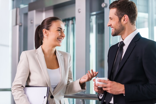 Reservando um tempo para conversar com o colega. dois alegres empresários discutindo algo e sorrindo