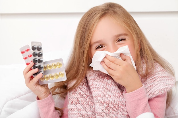 Resfriado y gripe. Una niña con pastillas en sus manos.